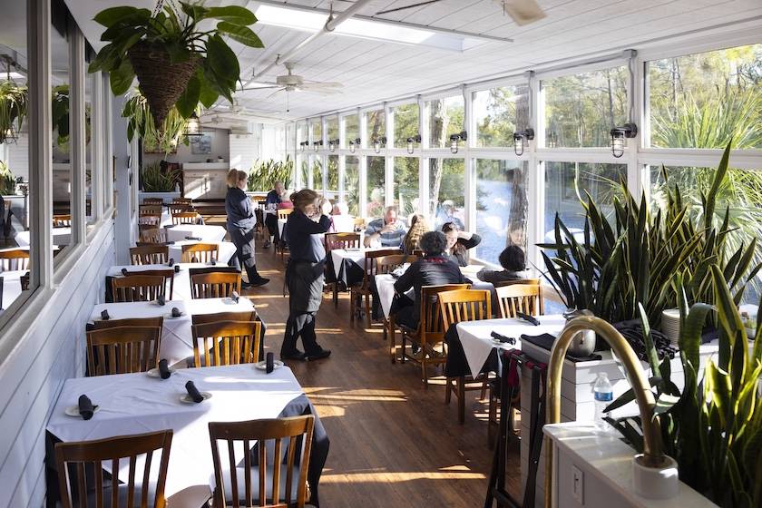 wait staff talking to guests in sunroom at Alexander's Restaurant