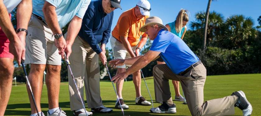 Doug Weaver adjusting the club position of one of several students during a golf lesson